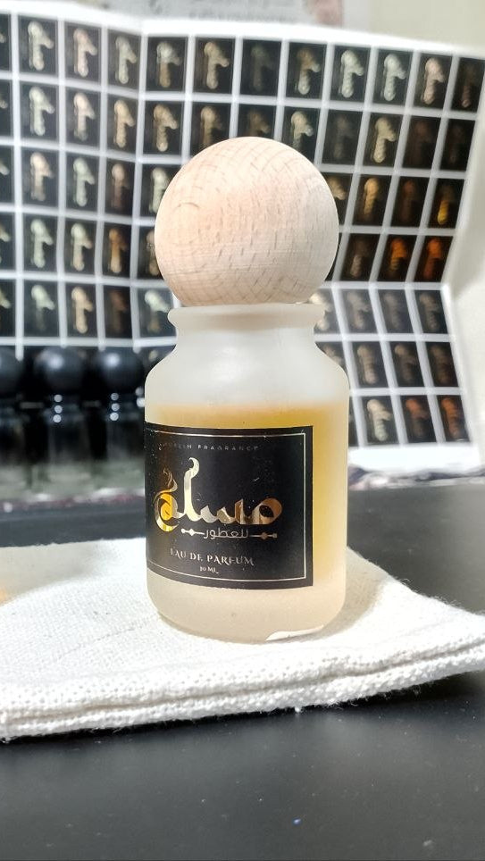 “IMAGINATION perfume bottle 50ml with crystal cap and ‘Musk Perfumes’ logo, light sky-blue liquid, surrounded by bergamot, lemon, ginger, tea, marine notes, amber and cedarwood in a fresh bright airy atmosphere.”